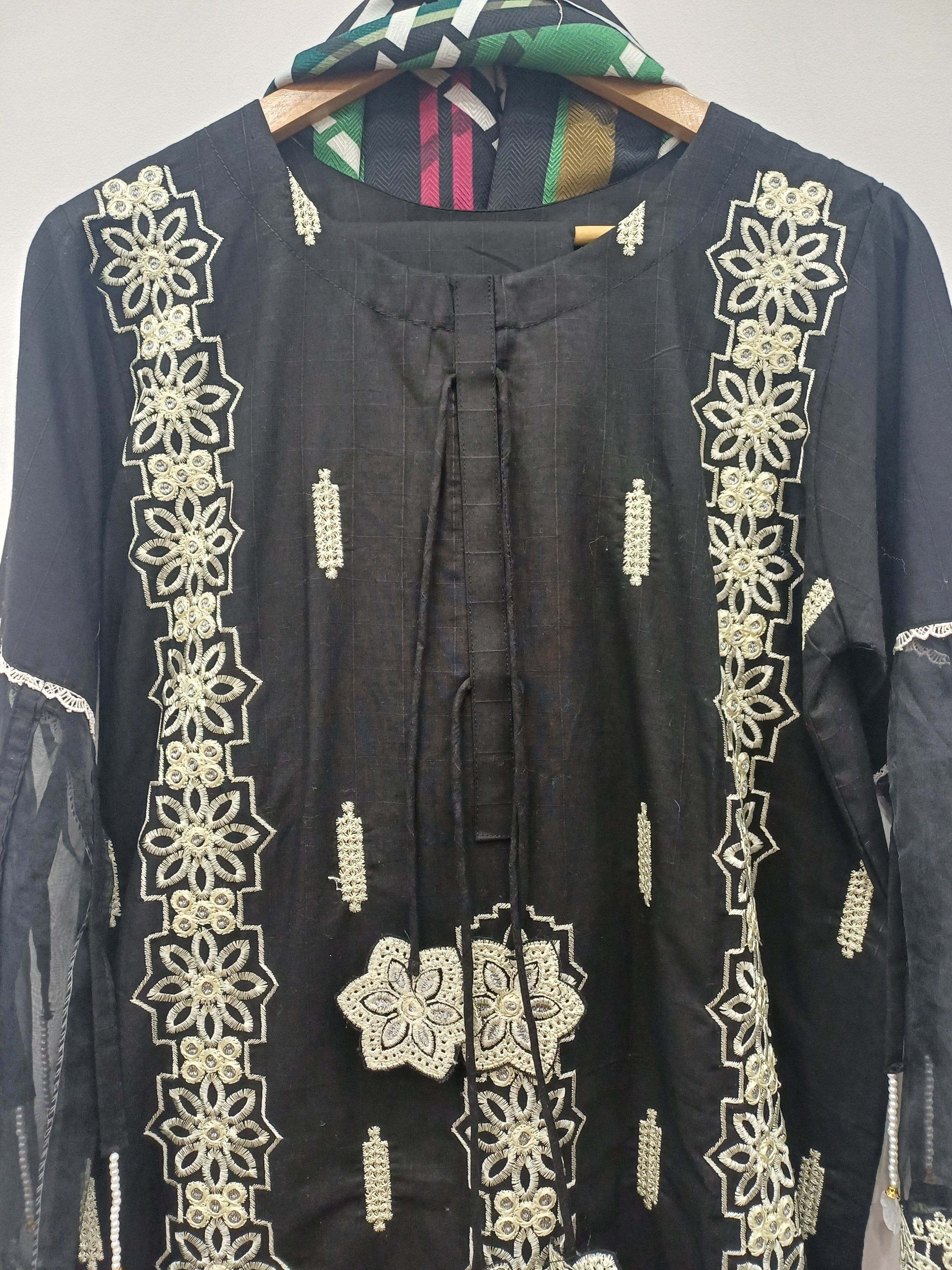 Close-up neckline tassel detail and embroidery on black kurta