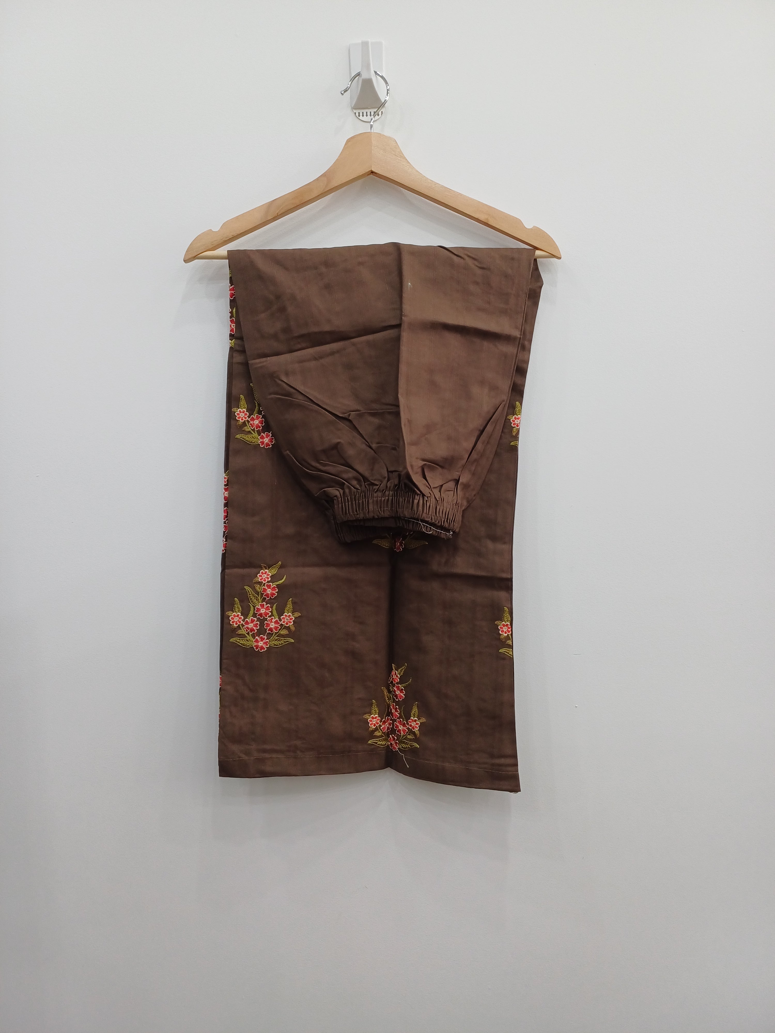 Folded brown pants with floral patterns on a white background