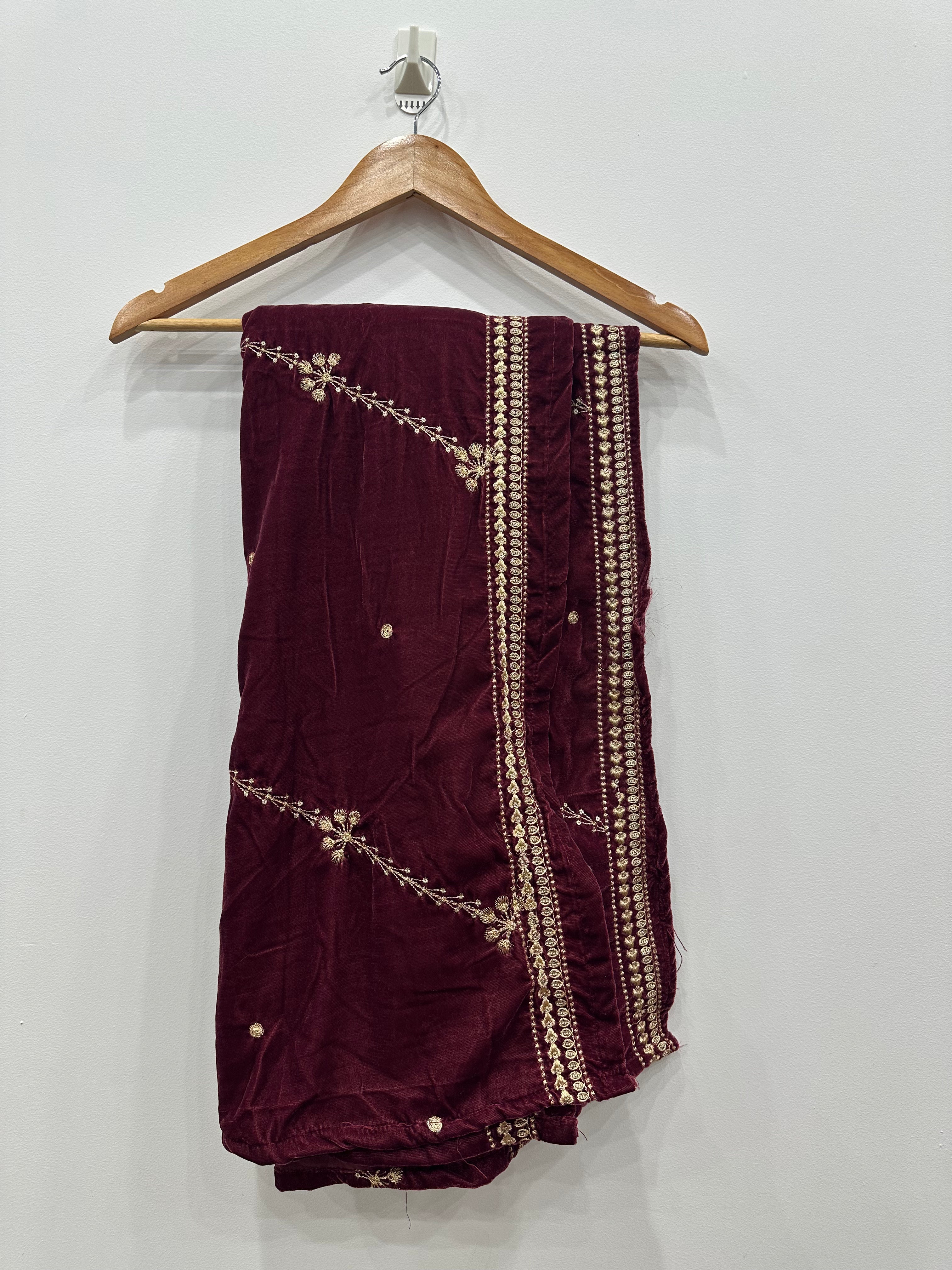 Maroon saree with gold embroidery on a wooden hanger against a white background