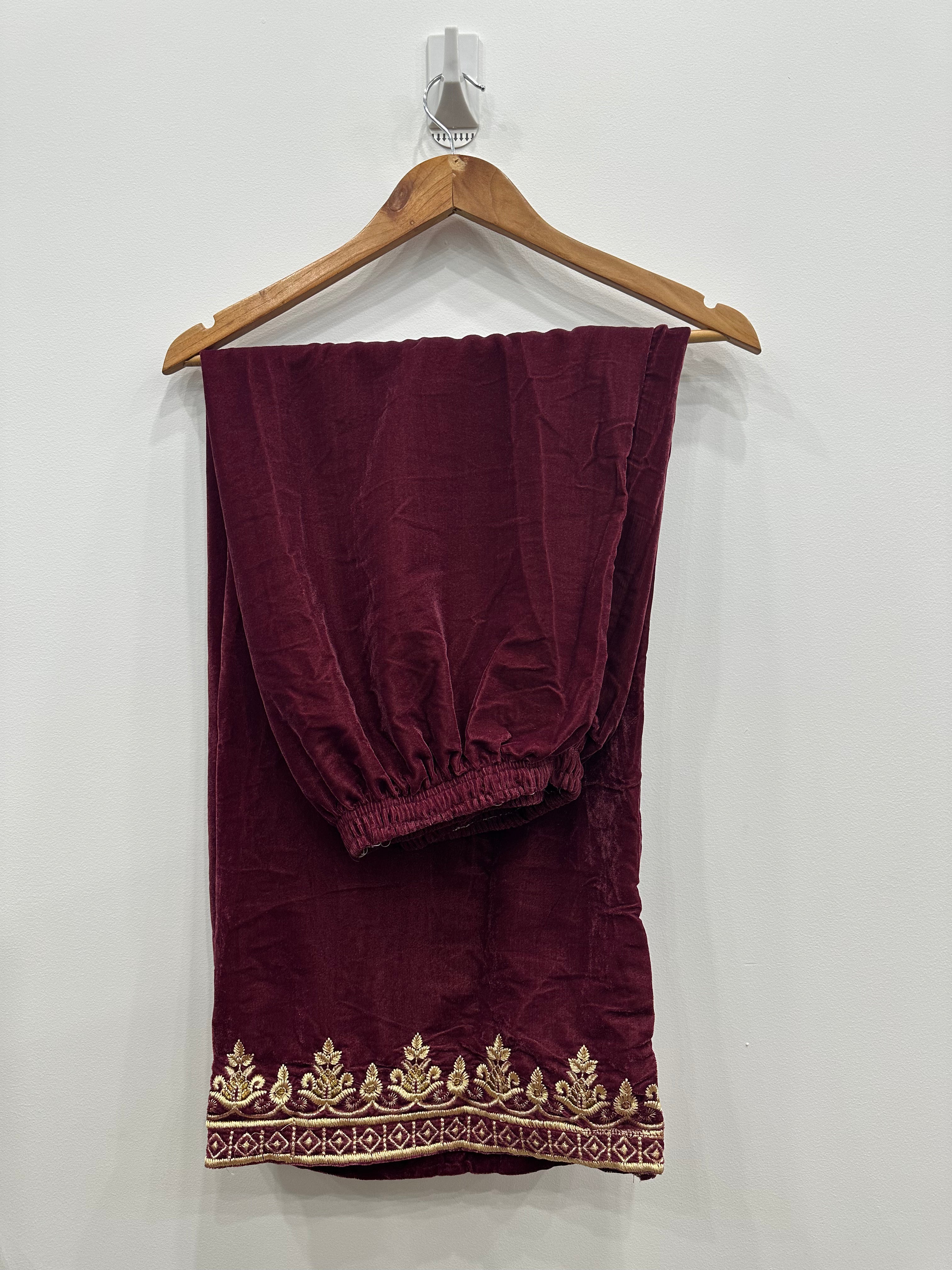 Embroidered hem on maroon velvet trouser (poincha detail)