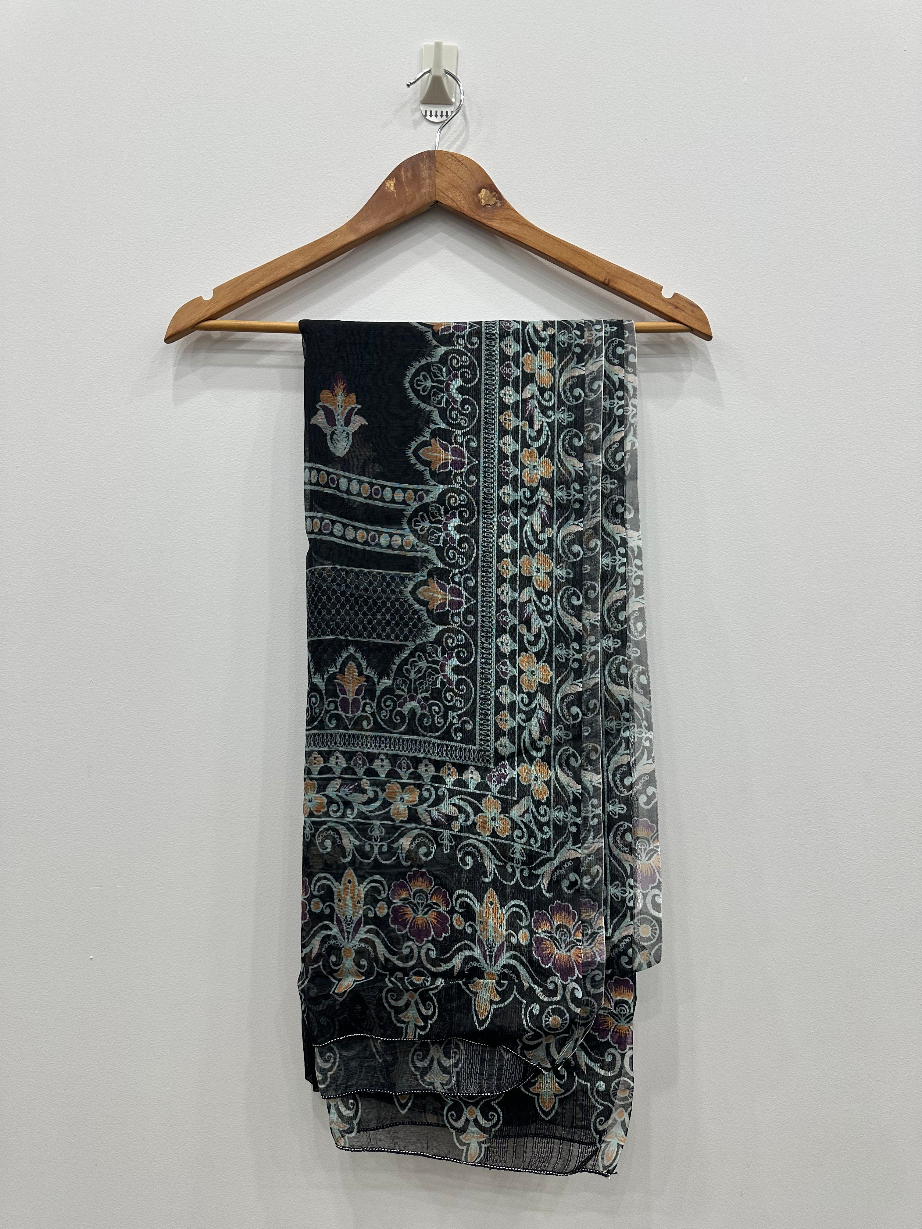 Black patterned scarf on a wooden hanger against a white background