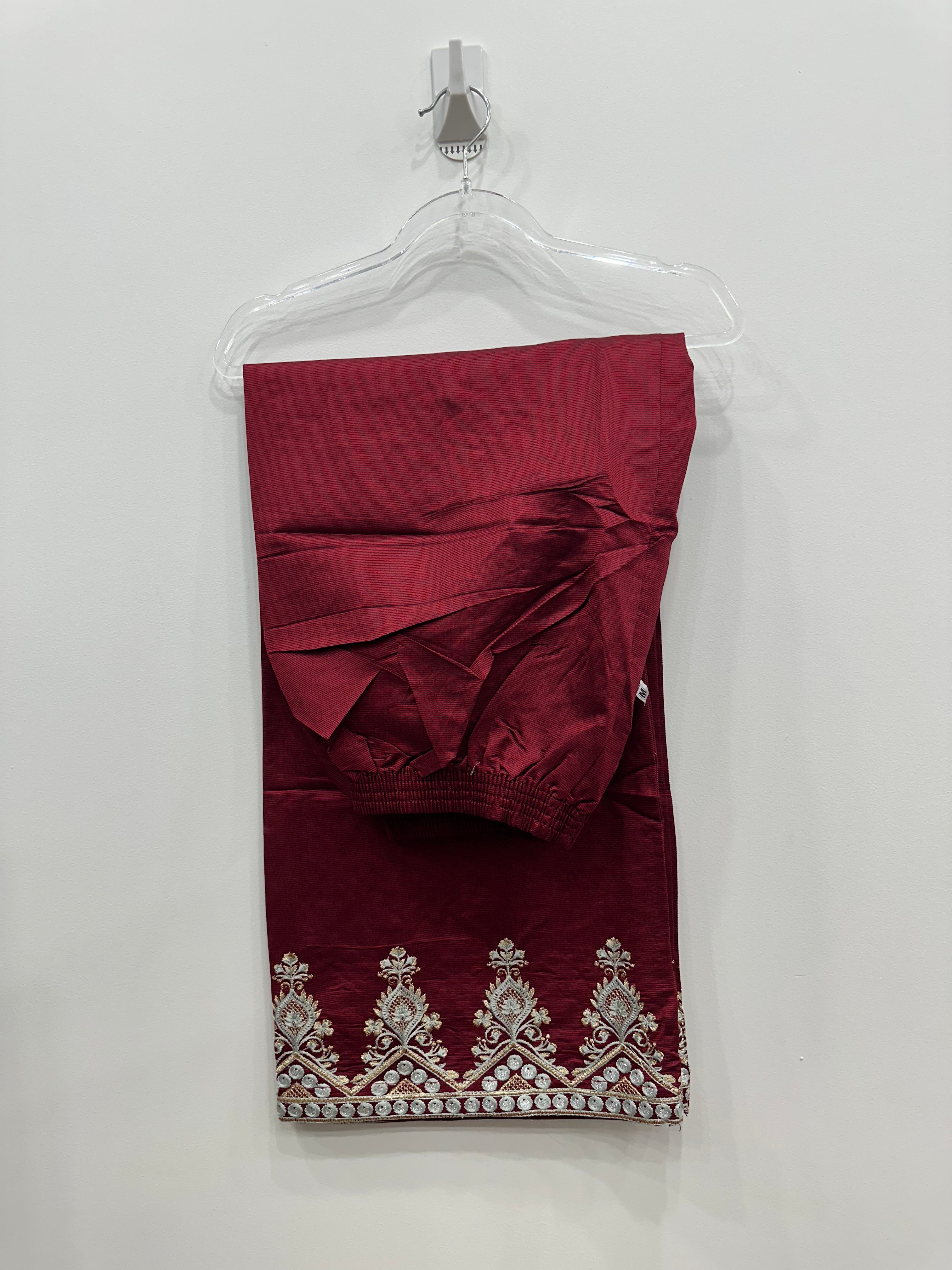 Maroon dress with intricate white embroidery on a clear hanger against a white background