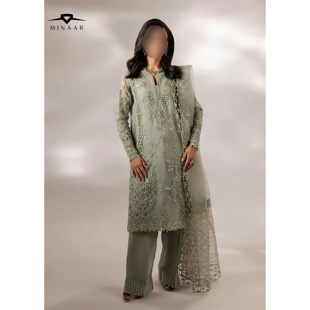 Woman wearing a light green embroidered outfit with a dupatta on a plain background, branded 'Minaar'.