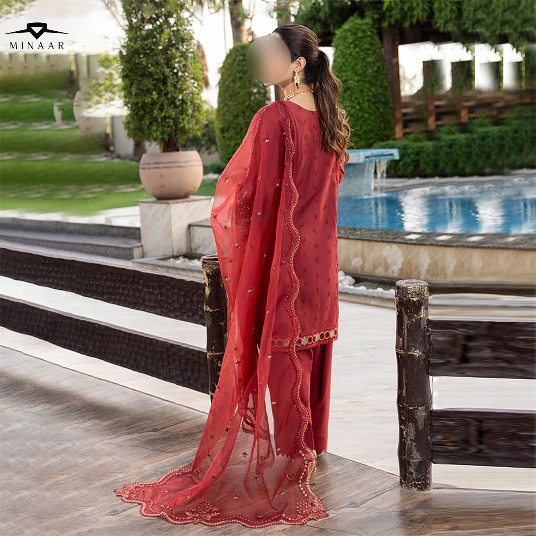Woman in a red traditional outfit standing by a pool with Minaar branding.