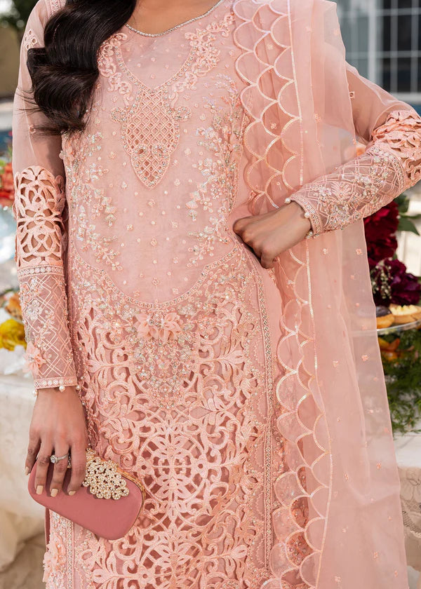 Woman wearing a pink embroidered traditional outfit with a matching dupatta.