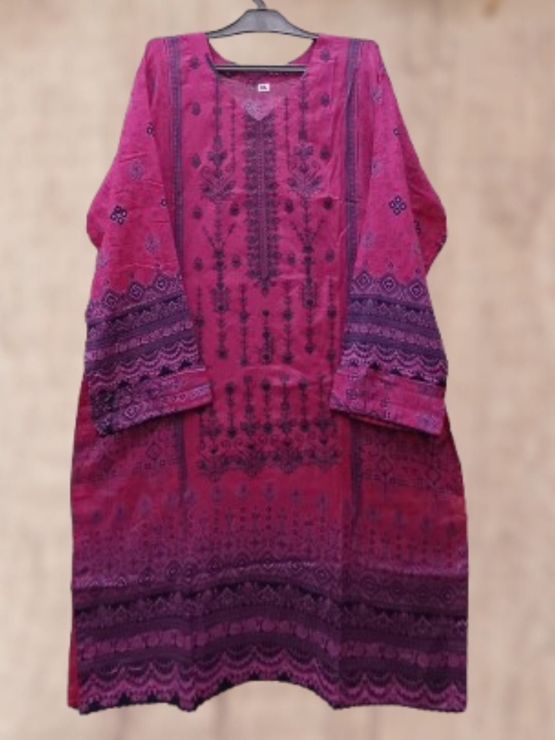 A magenta pink and purple embroidered kurta with intricate patterns, hanging on a black hanger against a neutral beige background.