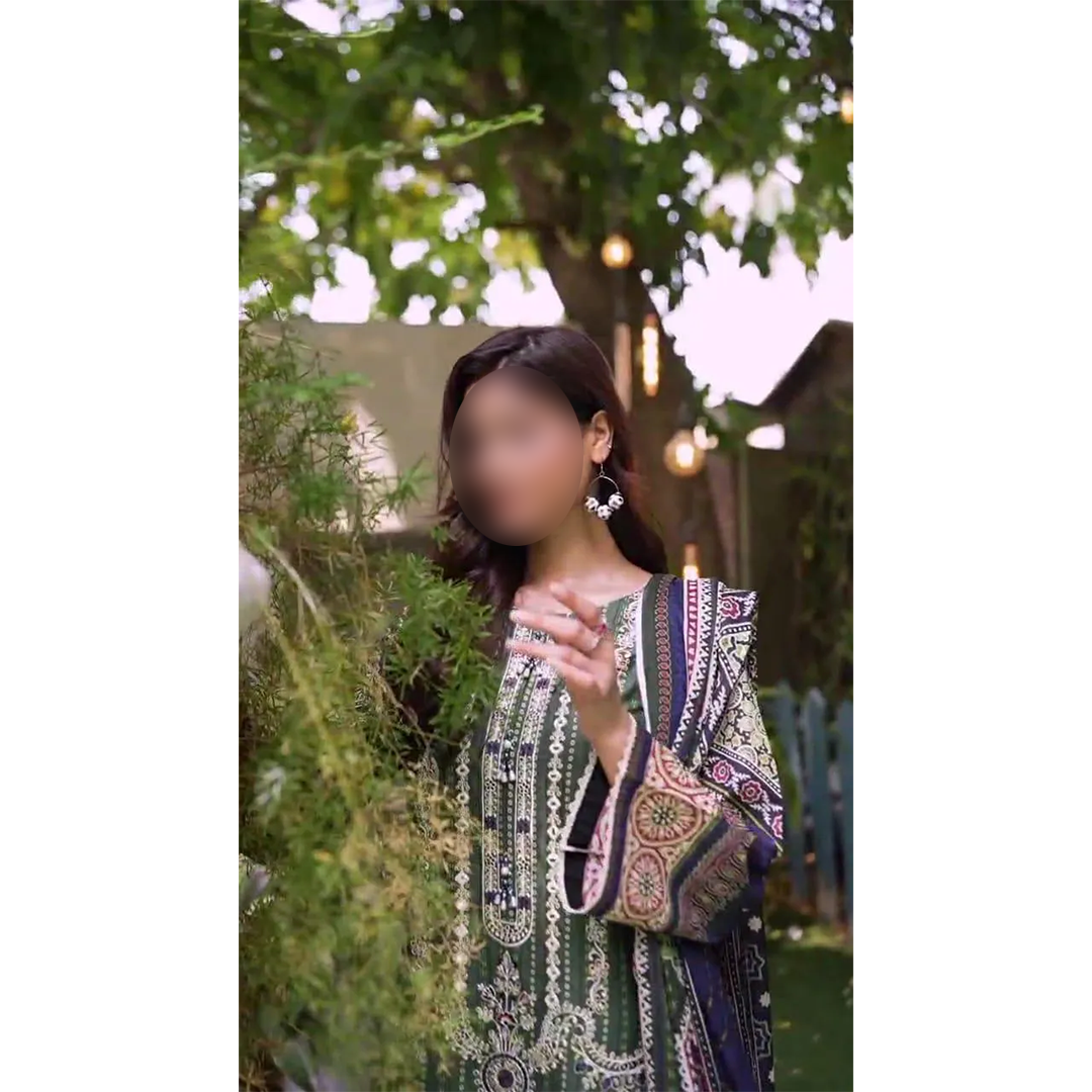 Person wearing a green and purple patterned dress in an outdoor setting with trees and lights.