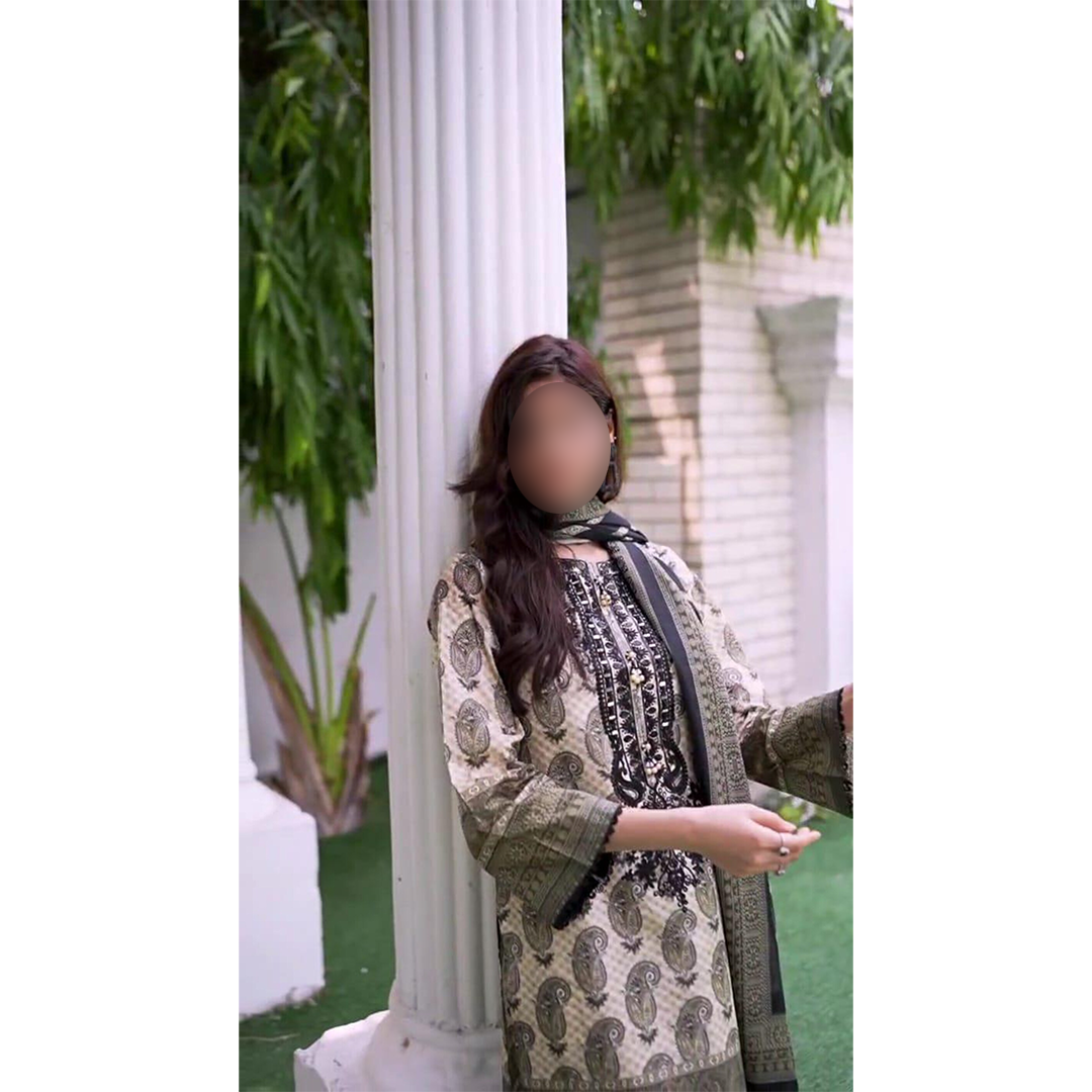 Person wearing a patterned outfit standing outdoors with greenery and white columns in the background