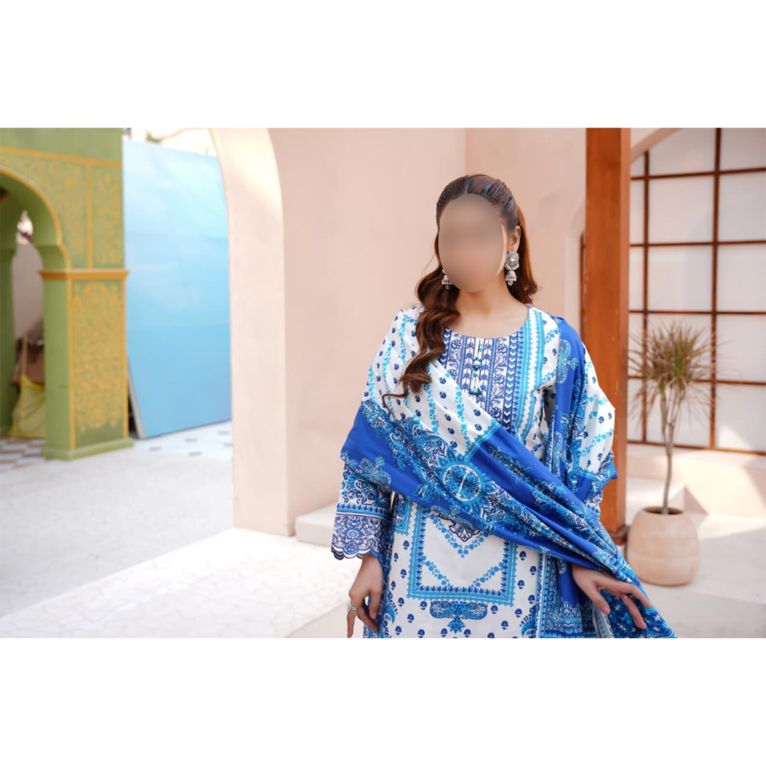 Woman wearing a blue and white patterned dress with a matching shawl in an outdoor setting.